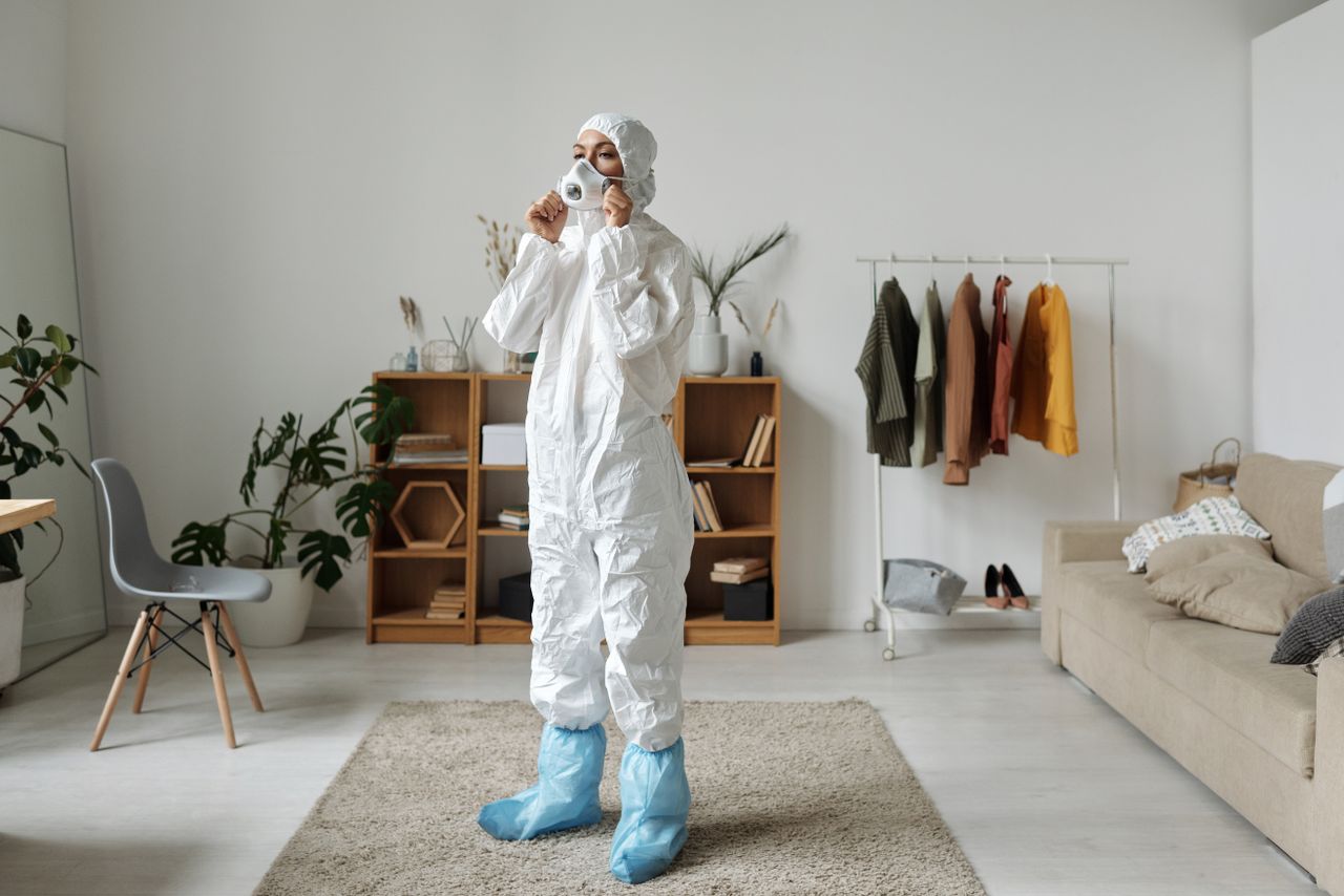 services-01 Woman in protective suit wearing face mask indoors with modern interior design.
